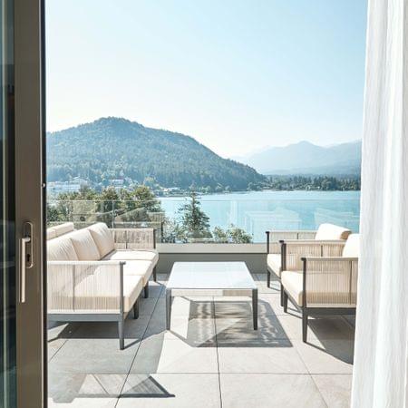 Modern terrace with lounge furniture overlooking lake and forested hills